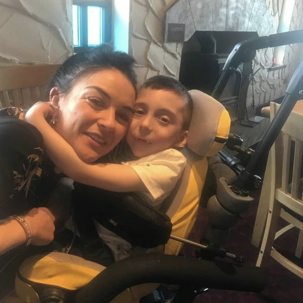 Oisin seated in his Chunc chair hugging his mum, both smiling and looking at the camera