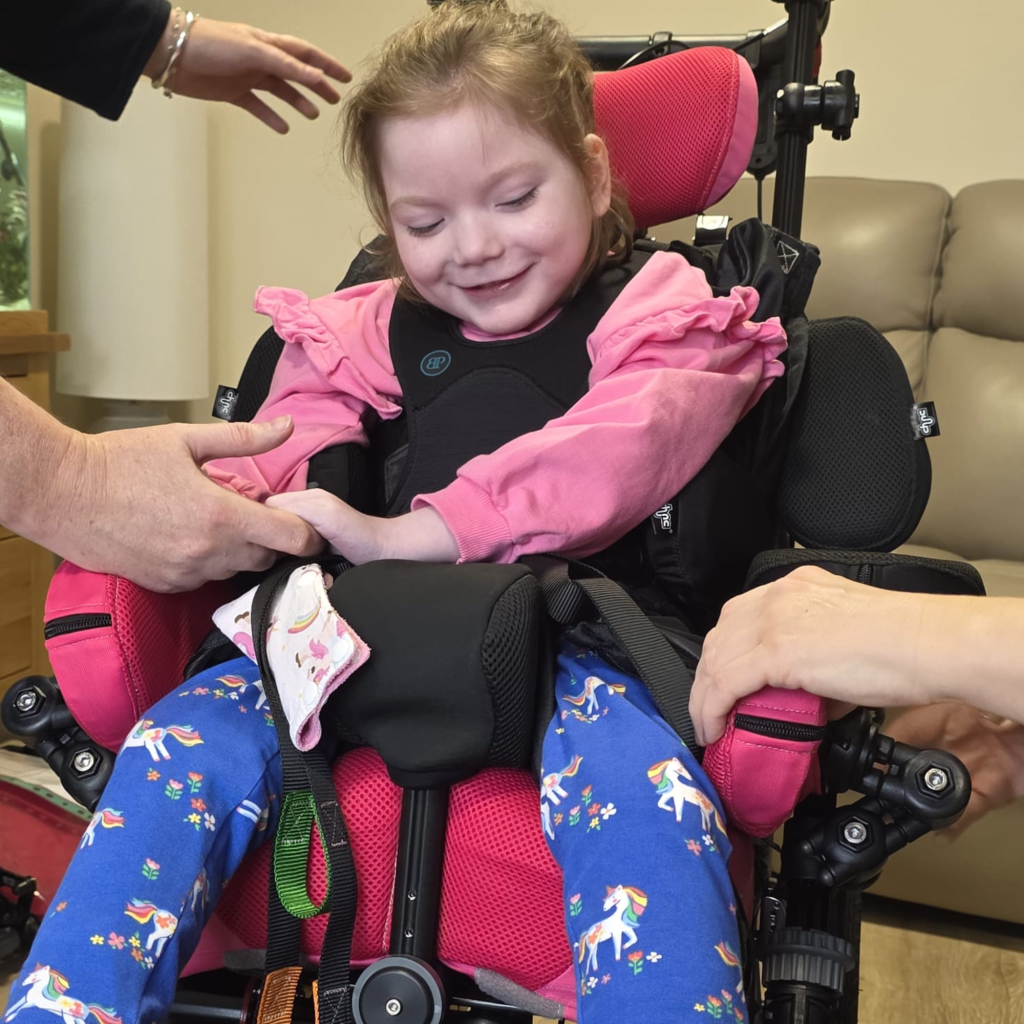 Skylar Rose seated in her Hilo chair smiling while looking down in a relaxed, supported position